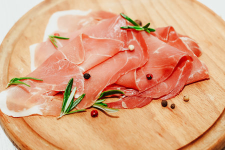 Pieces of dried pork jamon prosciutto on a wooden board.の写真素材