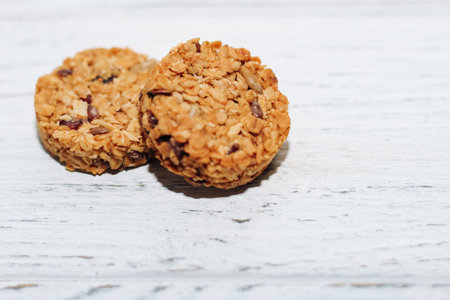 Round granola with oatmeal, dried fruits and seeds on a white table.の写真素材