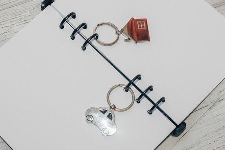 Notebook with rings, checkered sheets, keychain with a car and a house.の写真素材
