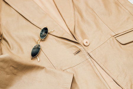 Gold-rimmed sunglasses on the texture of a brown leather jacket, genuine soft leather.の写真素材