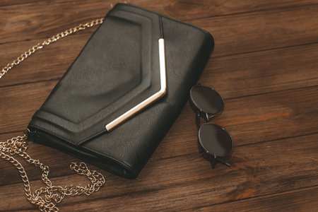 Black clutch bag with chain and iron-rimmed glasses.の写真素材