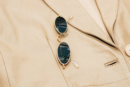 Gold-rimmed sunglasses on the texture of a brown leather jacket, genuine soft leather.の写真素材