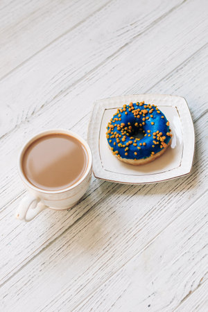 Coffee in a cup with a saucer with a donut in blue-yellow color.の写真素材