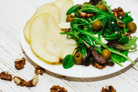 Salad with pears, herbs, arugula, prosciutto, cheese, green olives and nuts.の写真素材