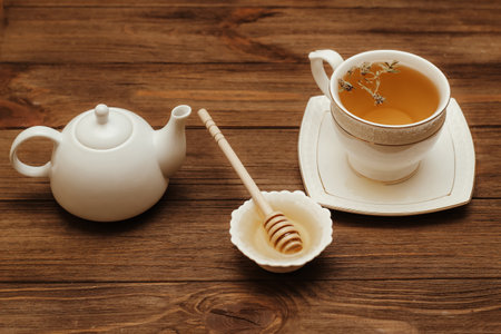 Liquid fresh linden honey in a plate with a wooden honey spoon and tea.の写真素材