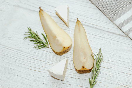 Pieces of ripe pear with Camembert cheese on the table.の写真素材