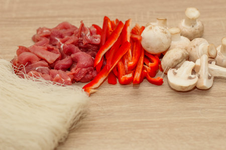 Sliced meat, mushrooms and red pepper on a board with rice glass noodles Funchoza.の写真素材
