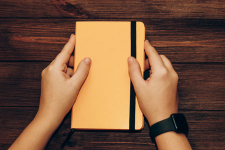 A black technological smart watch on the hand that holds a diary.の写真素材