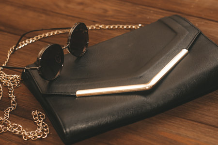 Black clutch bag with chain and iron-rimmed glasses.の写真素材