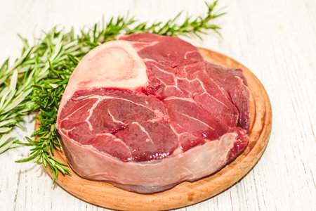 Fresh piece of meat large beef steak on the bone ossobuco with rosemary sprig.の写真素材