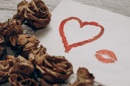 Drawn heart with lipstick on the background of dry roses, separation concept.の写真素材