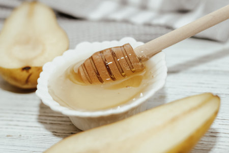 Liquid organic honey in white bowl, wooden honey spoon.の写真素材