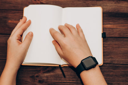 A black technological smart watch lies on a notepad for time management.の写真素材