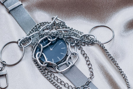 Stylish silver chain decorations for the neck and watch on a silk shiny background.の写真素材