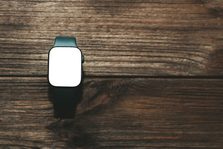 A black technological smart watch lies on a wooden background with a white screen for text spaceの写真素材