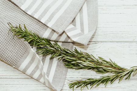 Fresh green sprig of rosemary seasoning on table with kitchen towel.の写真素材