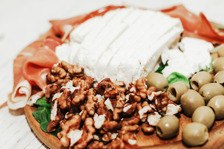 Pieces of dried pork jamon prosciutto with olives and cheese and nuts on the board.の写真素材