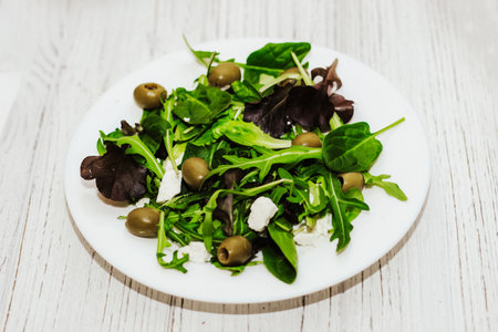 Salad leaves with arugula, cheese, green olives in a plate, healthy diet salad.の写真素材