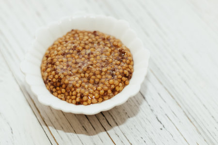 grain mustard in a white bowl on a white table.
