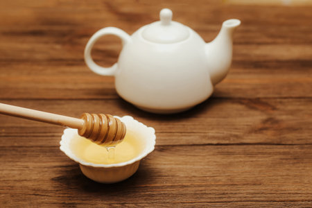 Liquid fresh linden honey in a plate with a wooden honey spoon and tea.の写真素材