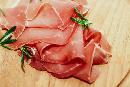 Pieces of dried pork jamon prosciutto on a wooden board.の写真素材