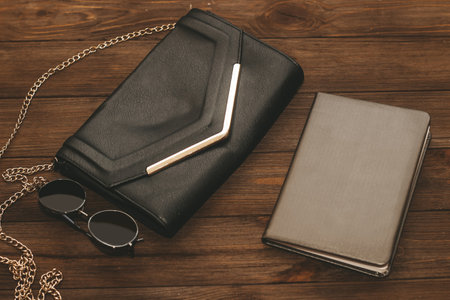 Black clutch bag with a chain and a notebook in a leather cover.の写真素材
