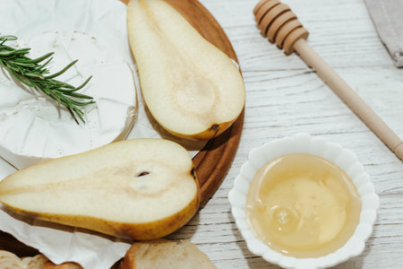 Camembert cheese with pear and rosemary sprig with honey on the table.の写真素材