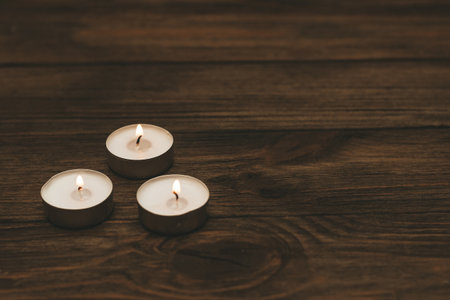 Three paraffin floating candles on a wooden table.の写真素材