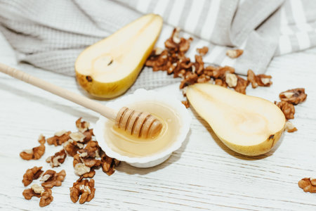 Liquid organic honey in white bowl with pears, wooden honey spoon.の写真素材