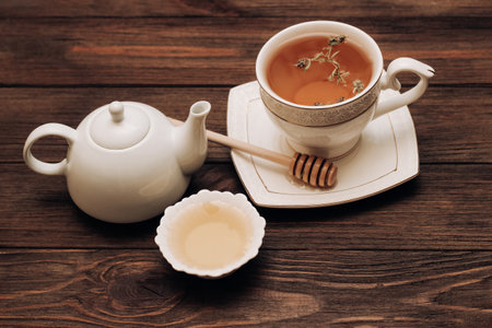 Liquid fresh linden honey in a plate with a wooden honey spoon and tea.の写真素材