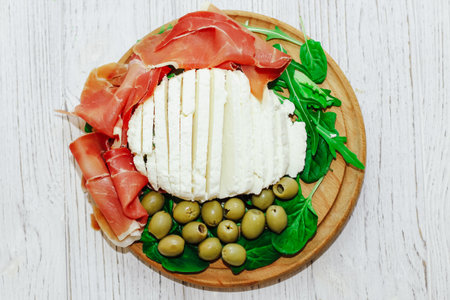 Pieces of dried pork jamon prosciutto with olives and cheese on the board.の写真素材