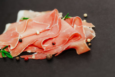 Pieces of dried pork jamon prosciutto on a black board.の写真素材