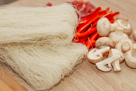 Sliced meat, mushrooms and red pepper on a board with rice glass noodles Funchoza.の写真素材