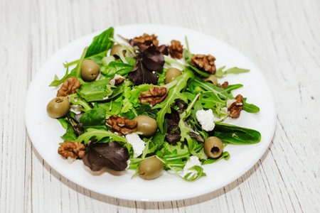 Salad leaves with arugula, cheese, green olives and nuts in a plate, healthy diet salad.の写真素材