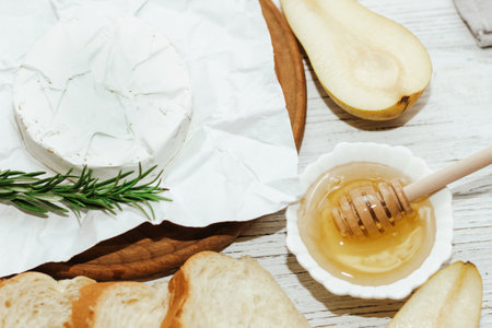 Camembert cheese with pear and rosemary sprig with honey on the table.の写真素材