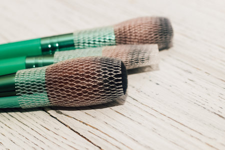Green makeup brushes on a wooden table.の写真素材
