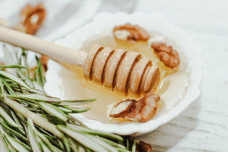 Liquid organic honey in white bowl, wooden honey spoon.の写真素材