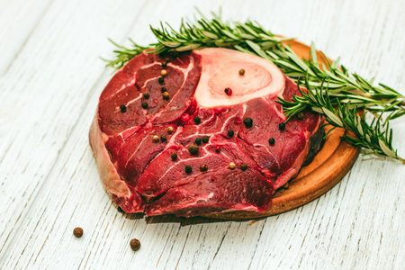 Fresh piece of meat large beef steak on the bone ossobuco with pepper, rosemary on the board.の写真素材
