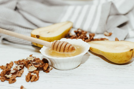 Liquid organic honey in white bowl with pears, wooden honey spoon.の写真素材