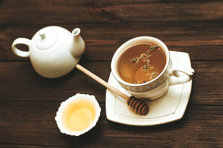 Liquid fresh linden honey in a plate with a wooden honey spoon and tea.の写真素材