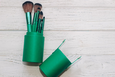 Green case with make-up bones on a wooden table.