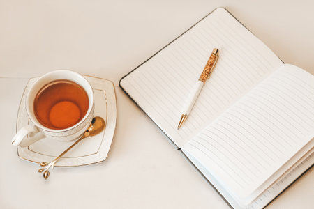 White cup and saucer with golden spoon and notepad.の写真素材