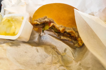 Bitten cheeseburger with cutlet and cucumbers close-up.の写真素材
