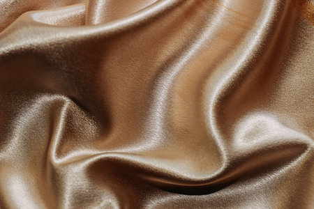 Golden shiny texture of silk satin satin with folds.の写真素材