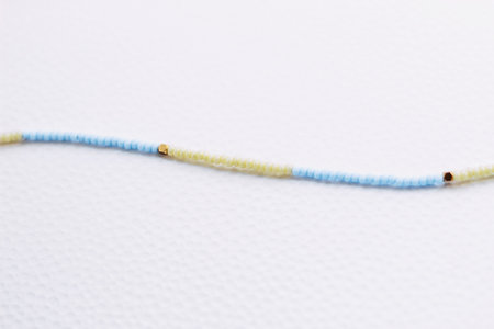 A necklace of yellow and blue beads on a white aesthetic background.の写真素材