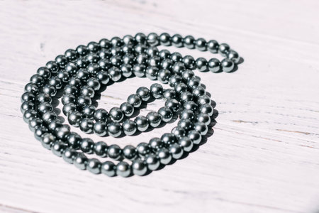 A necklace of gray beads on a white aesthetic background.の写真素材