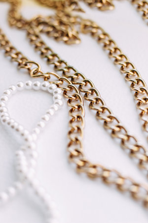 A necklace of white beads with chains of jewelry on a white aesthetic background.の写真素材