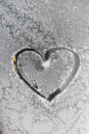 A drawn heart pattern on a frozen window.の写真素材