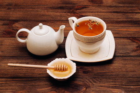 Liquid fresh linden honey in a plate with a wooden honey spoon and tea.の写真素材