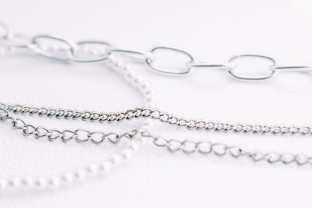 A necklace of white beads with chains of jewelry on a white aesthetic background.の写真素材